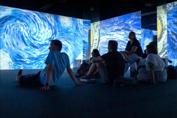 Family sitting on floor in front of Starry night projection